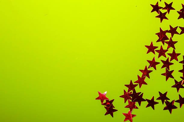 This vibrant, celebratory shot features red glitter stars clustered in the bottom right corner against a neon-lime green background, creating a playful and sparkling texture.