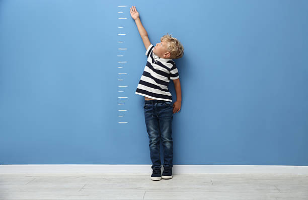 istock Cute little boy measuring his height near blue wall 2246541015