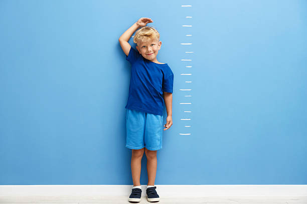 istock Cute little boy measuring his height near blue wall 2246541048