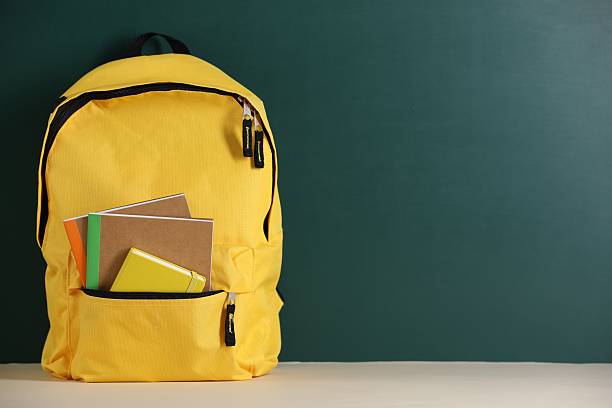 istock Yellow backpack with notebooks on table near blackboard. Space for text 2246541974