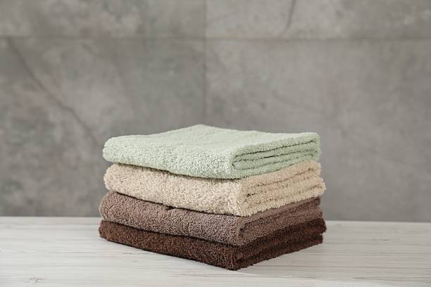 istock Stack of folded towels on light wooden table against grey wall 2246543033