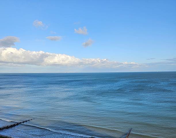 Blue water and low lying clouds in blue sky
