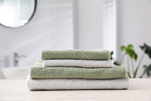 istock Stack of folded towels on light wooden table in bathroom, closeup 2246543160