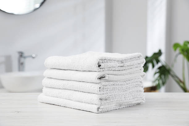 istock Stack of folded towels on light wooden table in bathroom, closeup 2246543186