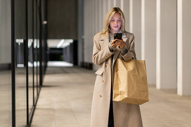 istock Woman walking and using her smart phone in modern urban exterior 2246543365