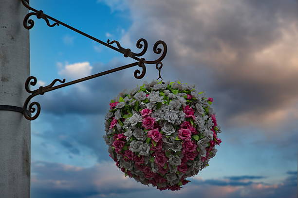 Bavarian village of Helen, Georgia traditional architecture building house in background with vertical view of lamp post and Brazilian jasmine red flower decorations and cloudy sky