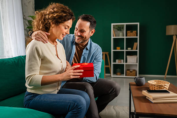 istock Happy couple exchanging a surprise gift at home 2246546483