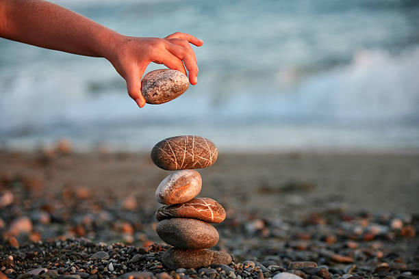 Children's hands making tower from rocks on the beach. Close up.