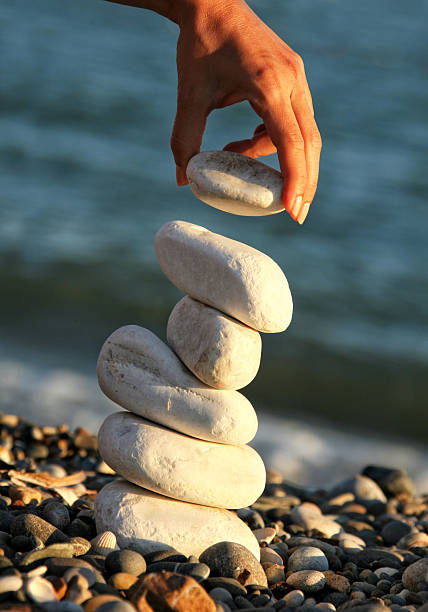 istock Young woman balancing stones on summer beach vacation 2246550046