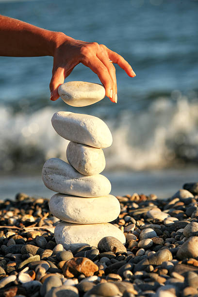 istock Young woman balancing stones on summer beach vacation 2246550089