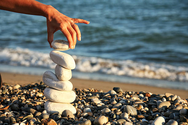 istock Young woman balancing stones on summer beach vacation 2246550099