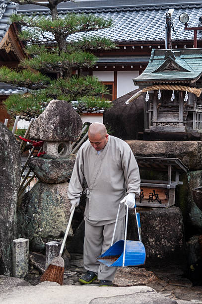 Hatsukaichi, Japan - December 31, 2019. An intimate look of a Japanese monk cleaning the temple grounds near the Daigan-ji temple on Miyajima island near hiroshima.