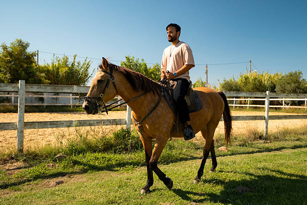 Mature woman getting ready for a horse ride. She is dressed in riders outfit. Exterior of horse ranch in Southern Serbia, Western Balkan.