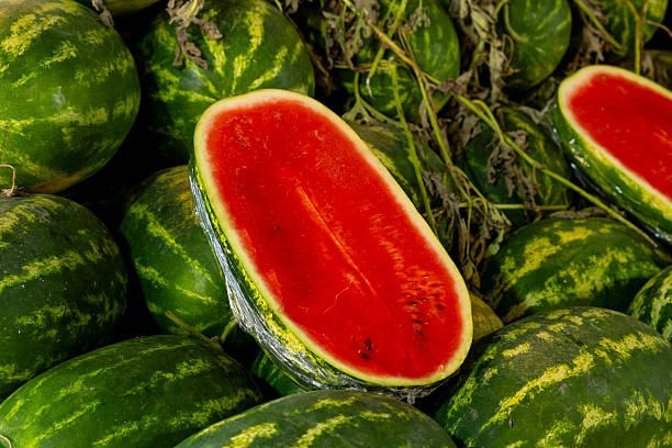 Display of whole and Cut watermelons at outdoor market.