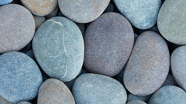 istock Pebbles stones on seashore  texture background for design web banner template page. many stones and they are different in color and size dry stones illuminated by sun 2246554463