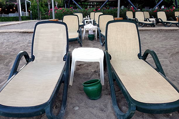 In the soft, golden light of sunset, a pair of sun loungers standing next to each other looks especially cozy and romantic. They seem to invite you to sit down and enjoy the magic of the moment when the sun touches the edge of the sea.