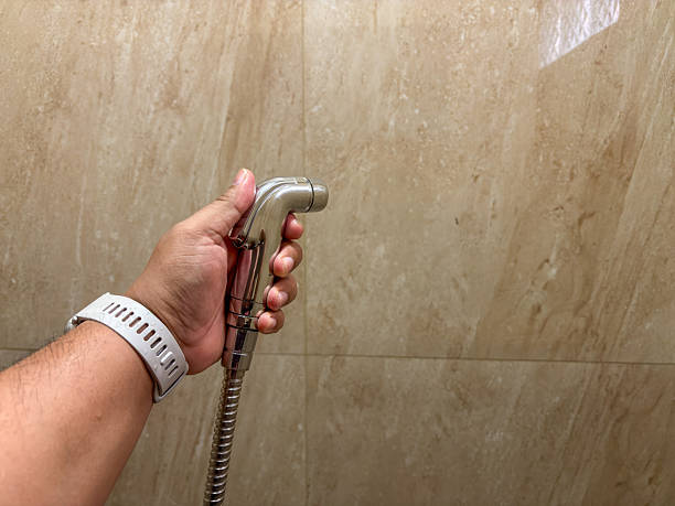 istock Hand holding bidet sprayer against marble wall in a bathroom setting indoor use 2246561245