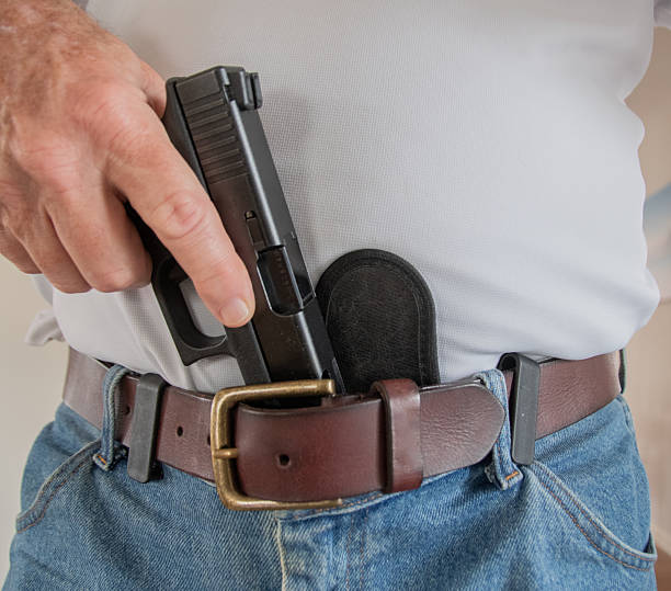 istock Man pulling a black semi-automatic handgun out of a gun holster 2246562391