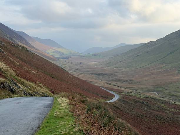A single track road snakes between the mountains of the Lake District between Braithwaite and Buttermere on a moody day