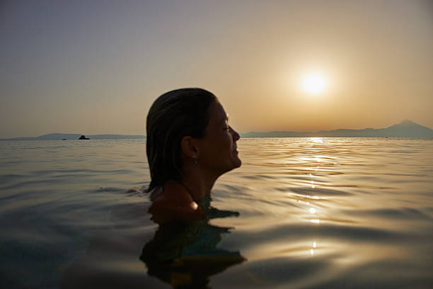 Woman swimming in calm sea, enjoying mount athos sunset view