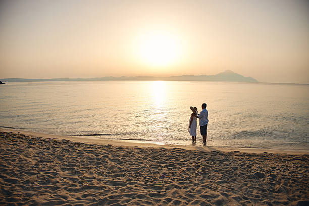 istock Couple enjoying romantic sunrise on sandy beach 2246569324