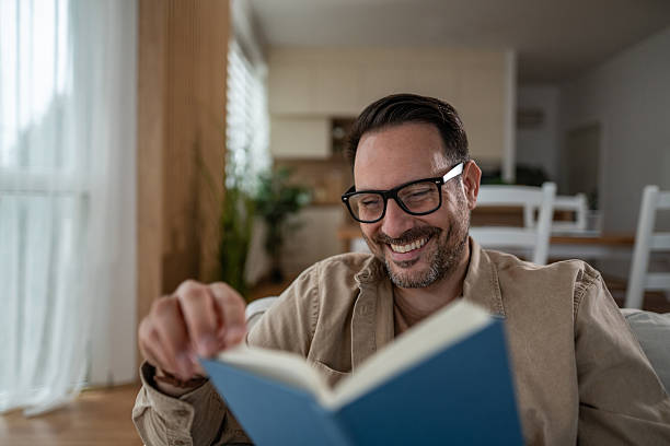 istock Happy man reading a book enjoying leisure time at home 2246570452
