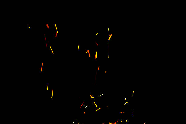 Burning red hot sparks fly from large fire in the night sky. Beautiful abstract background on the theme of fire, light and life.