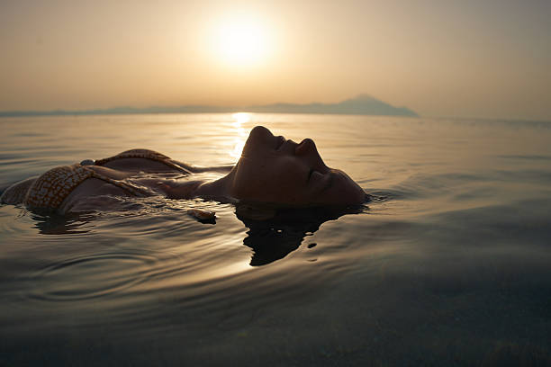 istock Woman floating on water relaxing during sunset or sunrise 2246571292
