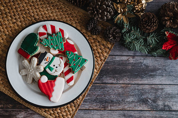 istock Christmas cookies on plate with golden lights on rustic table. Baking traditional snowman, tree, star cookies and santa hat for holidays 2246572527