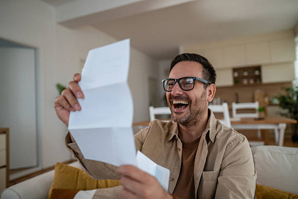 istock Man smiling reading good news letter at home 2246572547
