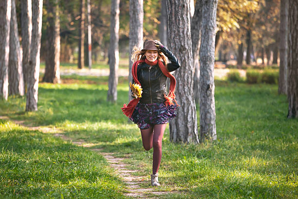 Parma, Italy - april 6 2024: Teenage Girl seen from behind and dressed in Punk Style making a phone Call with her Smartphone on a lawn