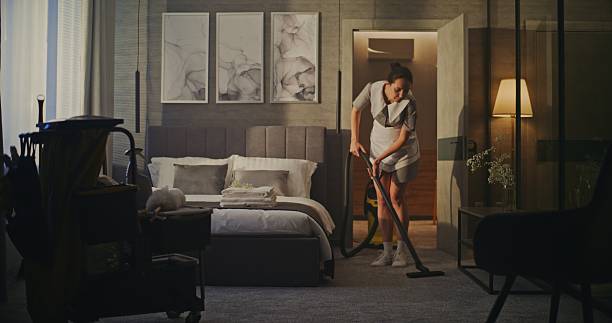 istock Professional Hotel Housekeeper Vacuuming Modern Guest Room 2246575511