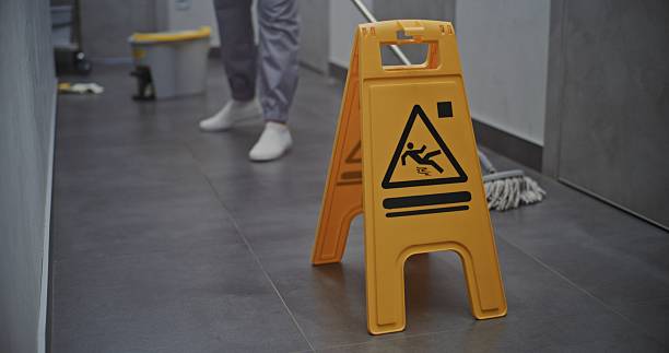 istock Maid Carefully Washes Floor While Bright Yellow Warning Sign Stands Beside 2246577346