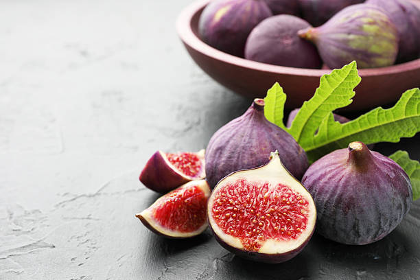 istock Fresh ripe figs and green leaf on dark textured table, closeup. Space for text 2246581622