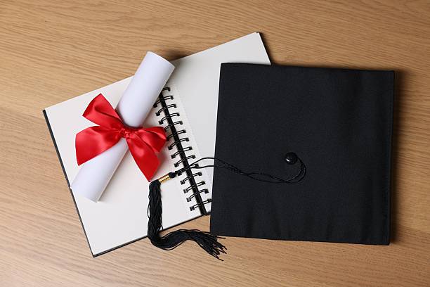 istock Graduation cap, diploma and notebook on wooden table, flat lay 2246585438