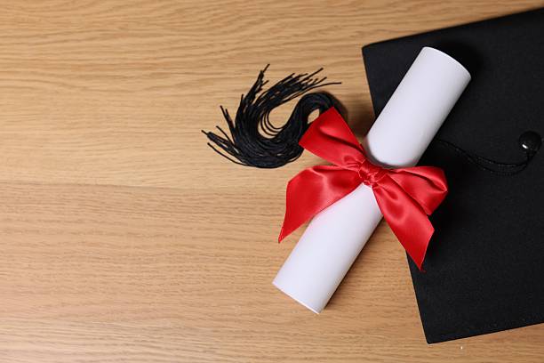 istock Graduation cap and diploma on wooden table, flat lay. Space for text 2246585488