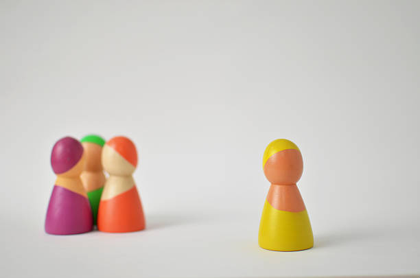 istock Wooden figure standing alone, separated from other colorful figures, representing exclusion 2246586826