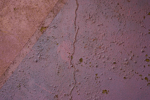 Close-up shot of a wall with cracked and weathered surface showing various colors and textures.