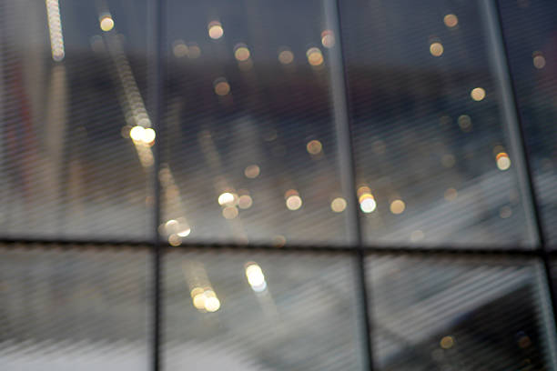 Blurred lights reflection on glass windows showing an urban abstract scene with soft light spots.