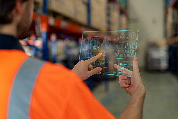 istock A staff member in a large warehouse uses a digital monitor to command a robotic arm, selecting items from racks with precision. The moment reflects big data analytics, automation, and efficiency in modern distribution and logistics. 2246599394