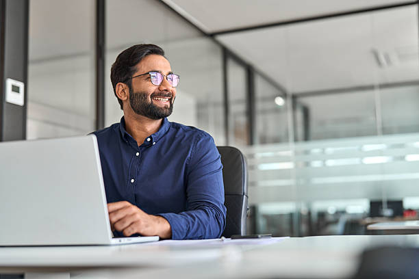 istock Happy Indian business man ceo executive looking away working on laptop. 2246601193