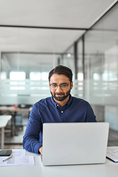 istock Busy Indian company employee worker using laptop working in office. Vertical 2246601198