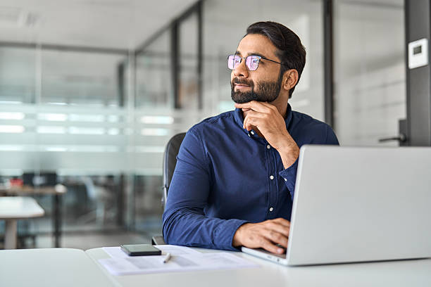 istock Happy Indian business man worker thinking looking aside working on laptop. 2246601201