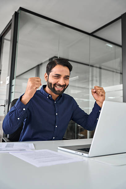 istock Happy professional Indian business man celebrating win using laptop at work. 2246601845