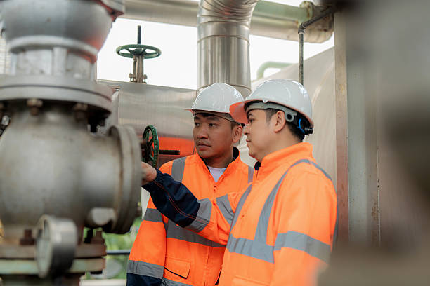 istock Two safety engineers stand beside heavy machinery in an oil refinery, analyzing pipeline layouts and planning maintenance schedules. The scene reflects fuel production, petrochemical operations, quality control, and modern industrial engineering workflows 2246603938