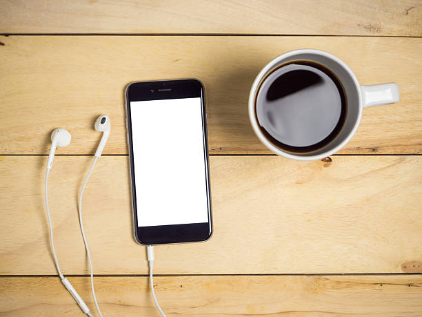 istock Blank screen smartphone with coffee and earphone on wooden table. 2246619426
