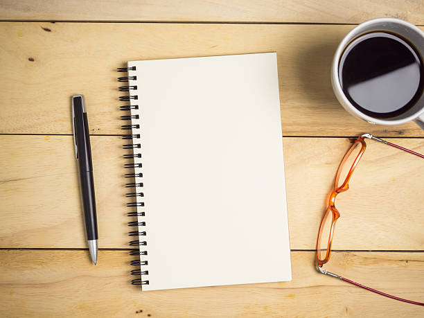 istock Blank notebook with pen, glasses & coffee on wooden table. 2246619436