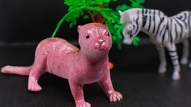 istock Pink Weasel and Zebra Figurines Positioned Near a Miniature Tree on a Dark Background, Emphasizing Animal, Toy, and Wildlife Concepts 2246620089
