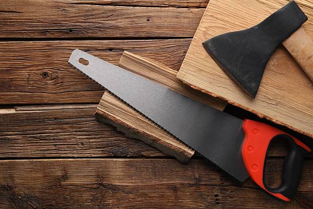 istock Saw with colorful handle, axe and logs on wooden background, flat lay. Space for text 2246624754