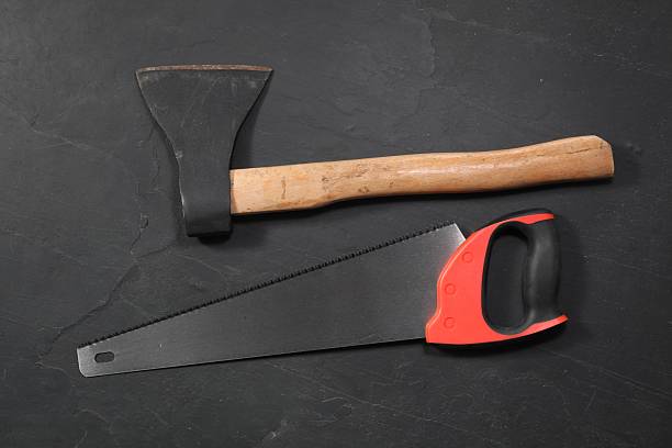 istock Saw with colorful handle and axe on black textured background, flat lay 2246624777